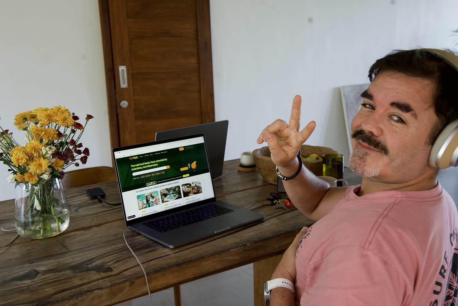 Robbie Lockie mit Kopfhörern am Laptop bei der Arbeit an foodfacts, er zeigt ein Peace-Zeichen in die Kamera