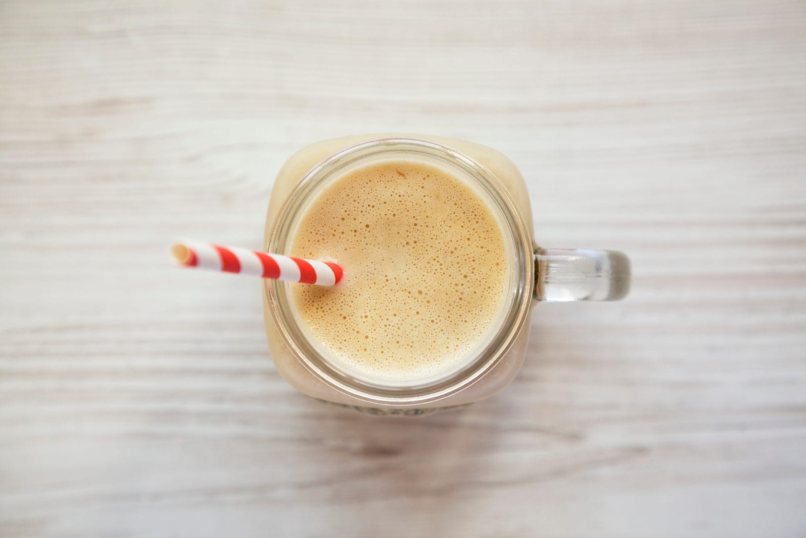 Erdnussbutter-Bananen-Smoothie im Glas mit Strohhalm von oben fotografiert