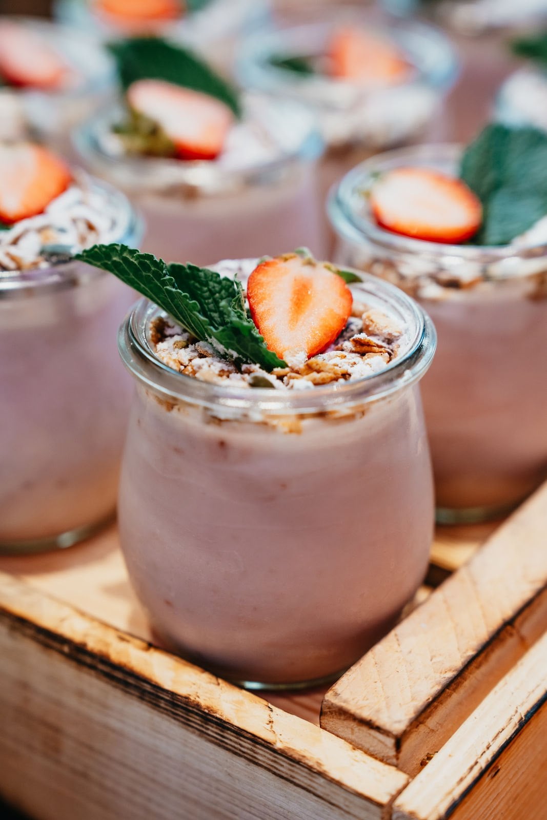 Two vegan strawberry desserts in glasses with granola and a fresh strawberry on top