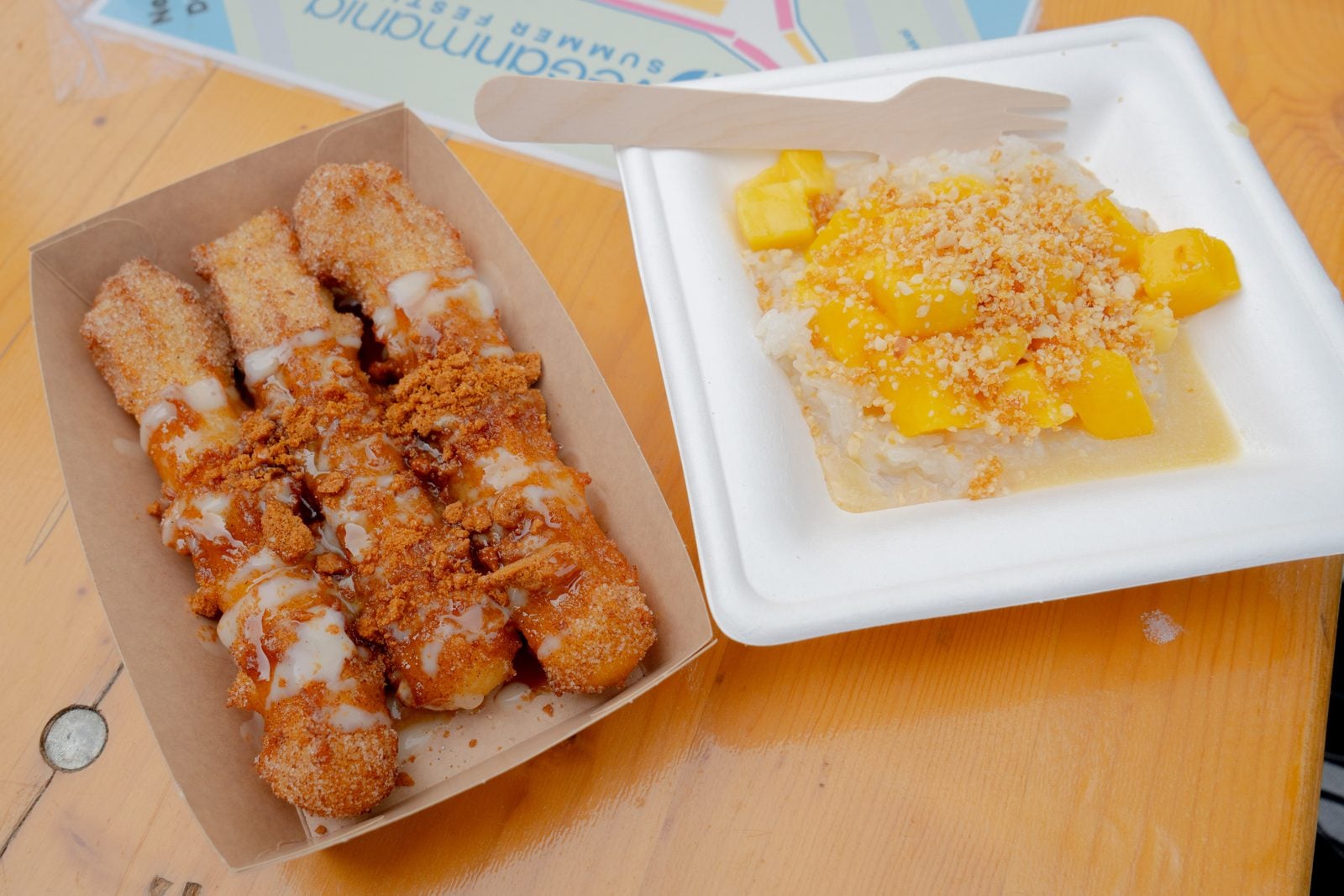 Vegane Churros mit Zimt und Keksstreuseln neben einem Teller Mango Sticky Rice auf einem Holztisch