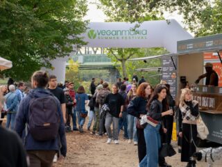 Eingangsbogen der VeganMania Summer Festival auf der Donauinsel Wien mit Besucherinnen und Besuchern und Foodtruck