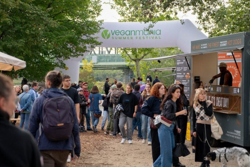 Eingangsbogen der VeganMania Summer Festival auf der Donauinsel Wien mit Besucherinnen und Besuchern und Foodtruck