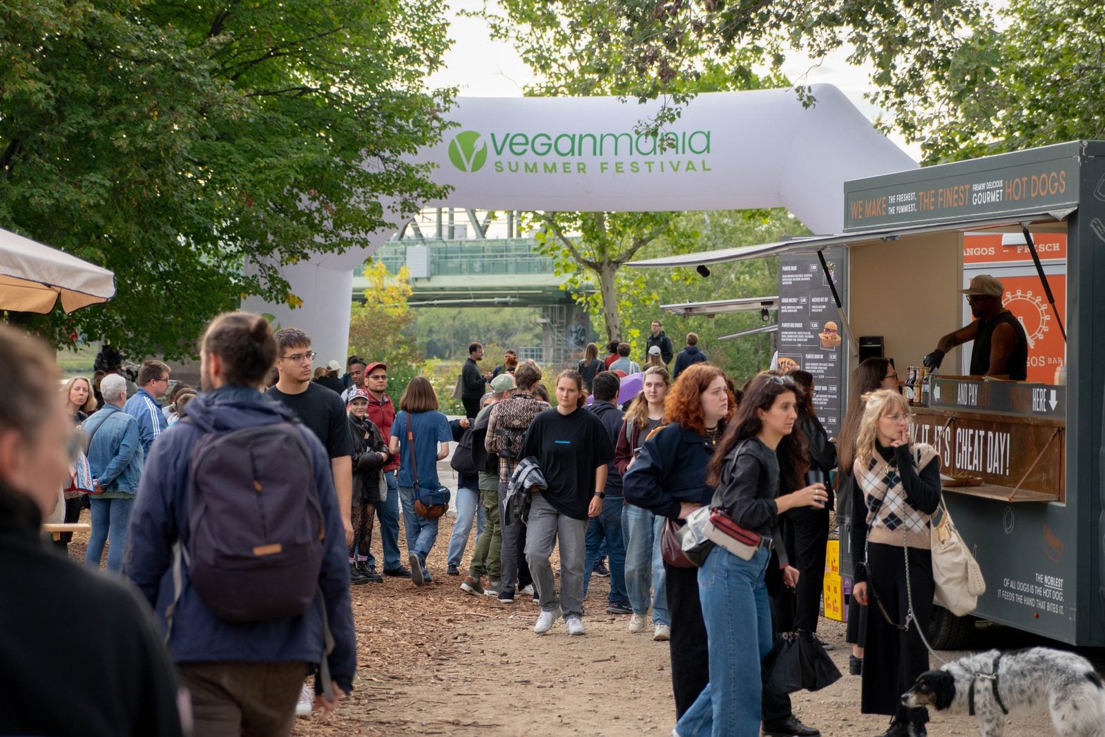 Eingangsbogen der VeganMania Summer Festival auf der Donauinsel Wien mit Besucherinnen und Besuchern und Foodtruck
