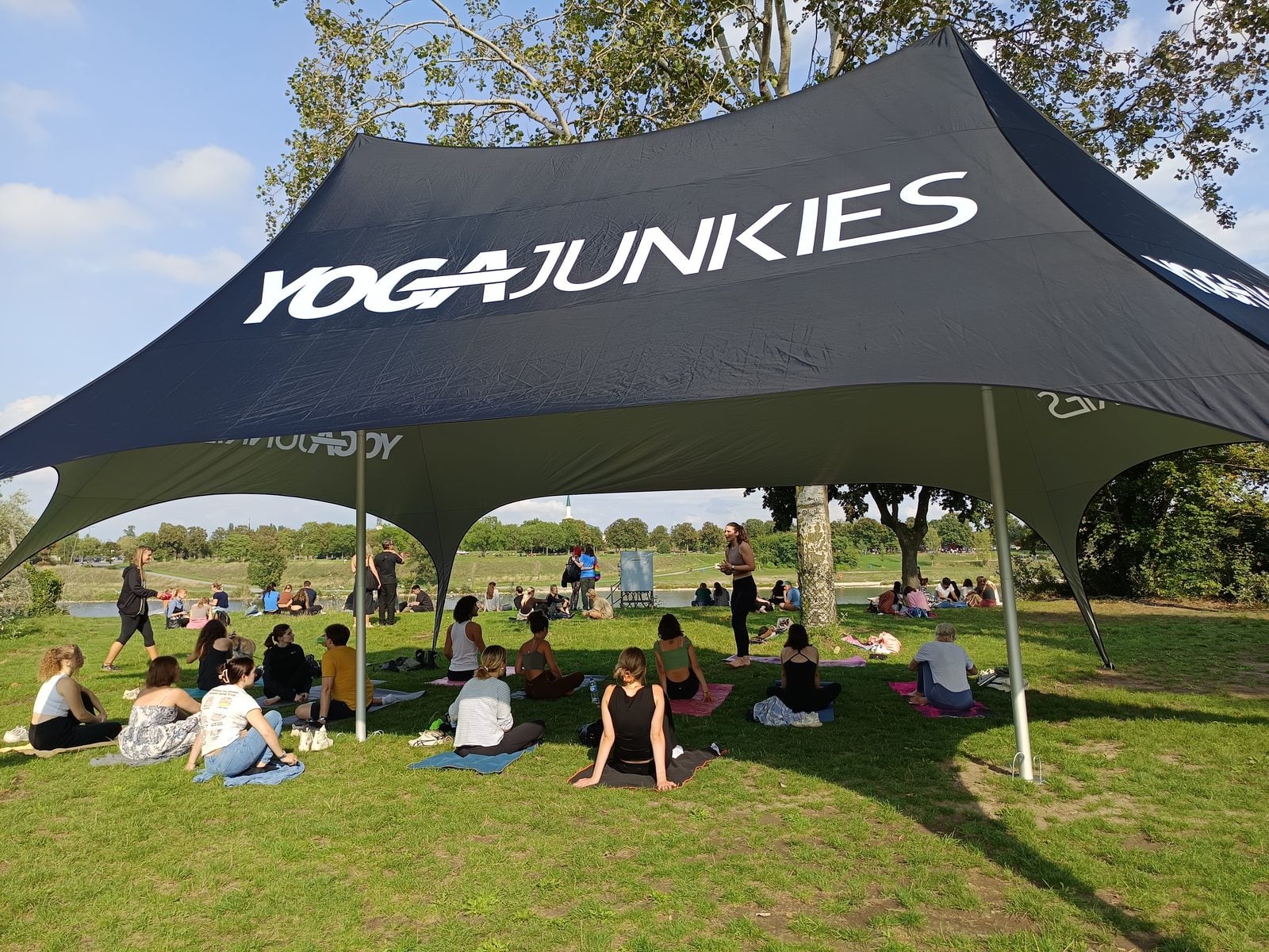 Yoga-Teilnehmerinnen auf Matten unter dem Zelt der Yoga Junkies Flow Area an der Neuen Donau