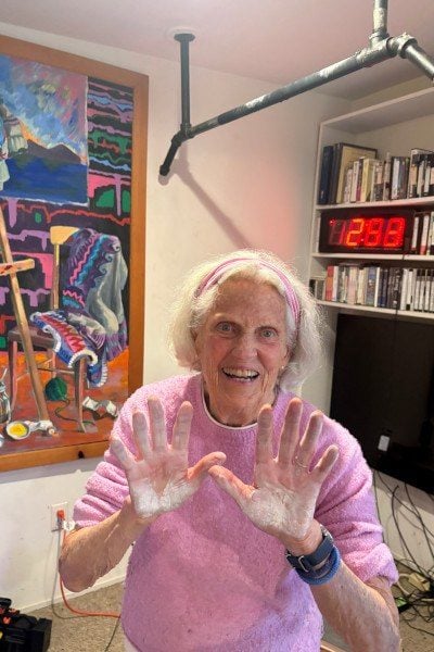 Ann Esselstyn zeigt lachend ihre mit Magnesia bedeckten Handflächen, im Hintergrund die Uhr mit 2:52