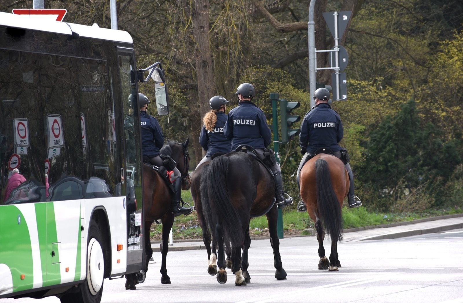 Drei berittene Polizeibeamte auf Pferden im Straßenverkehr einer deutschen Stadt