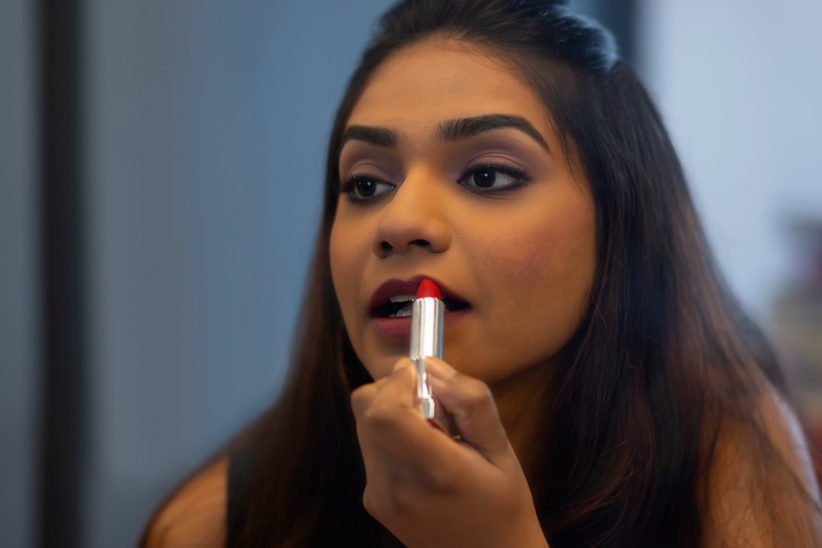 Junge Frau trägt vor dem Spiegel roten Lippenstift auf
