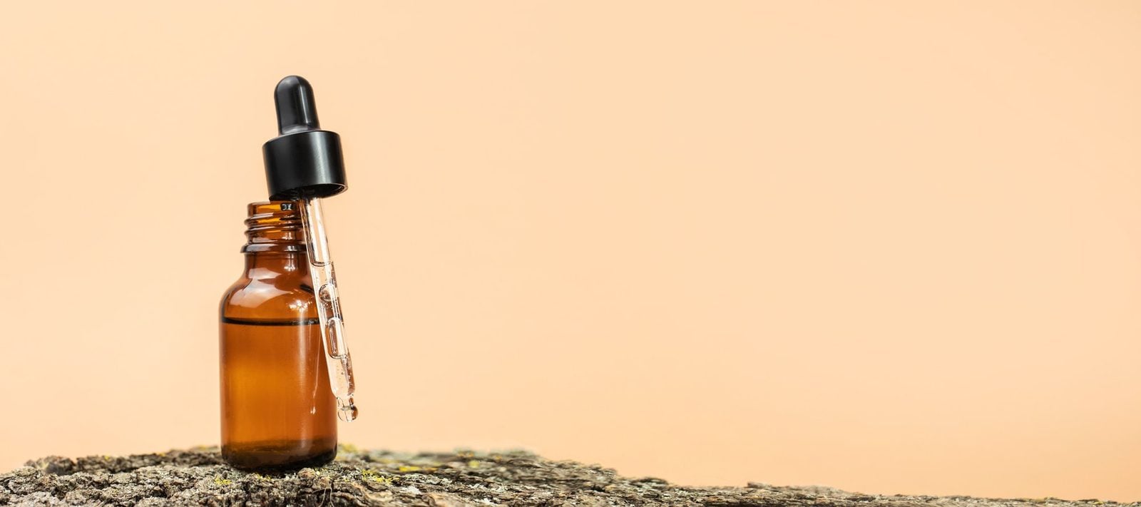 Braunglasflasche mit Pipette für Gesichtsserum auf Naturuntergrund