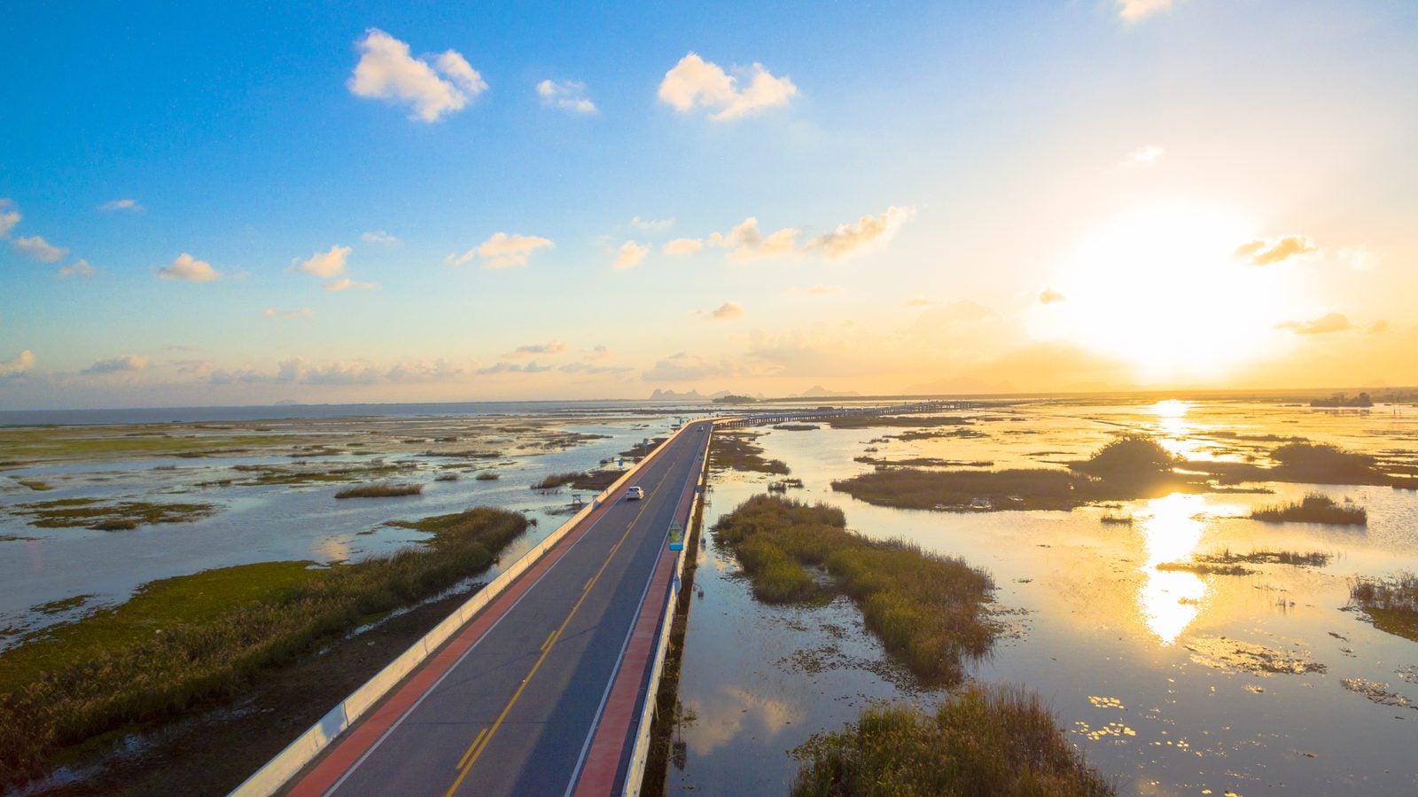 Lange Straßenbrücke über das Feuchtgebiet Thale Noi in Phatthalung bei Sonnenuntergang