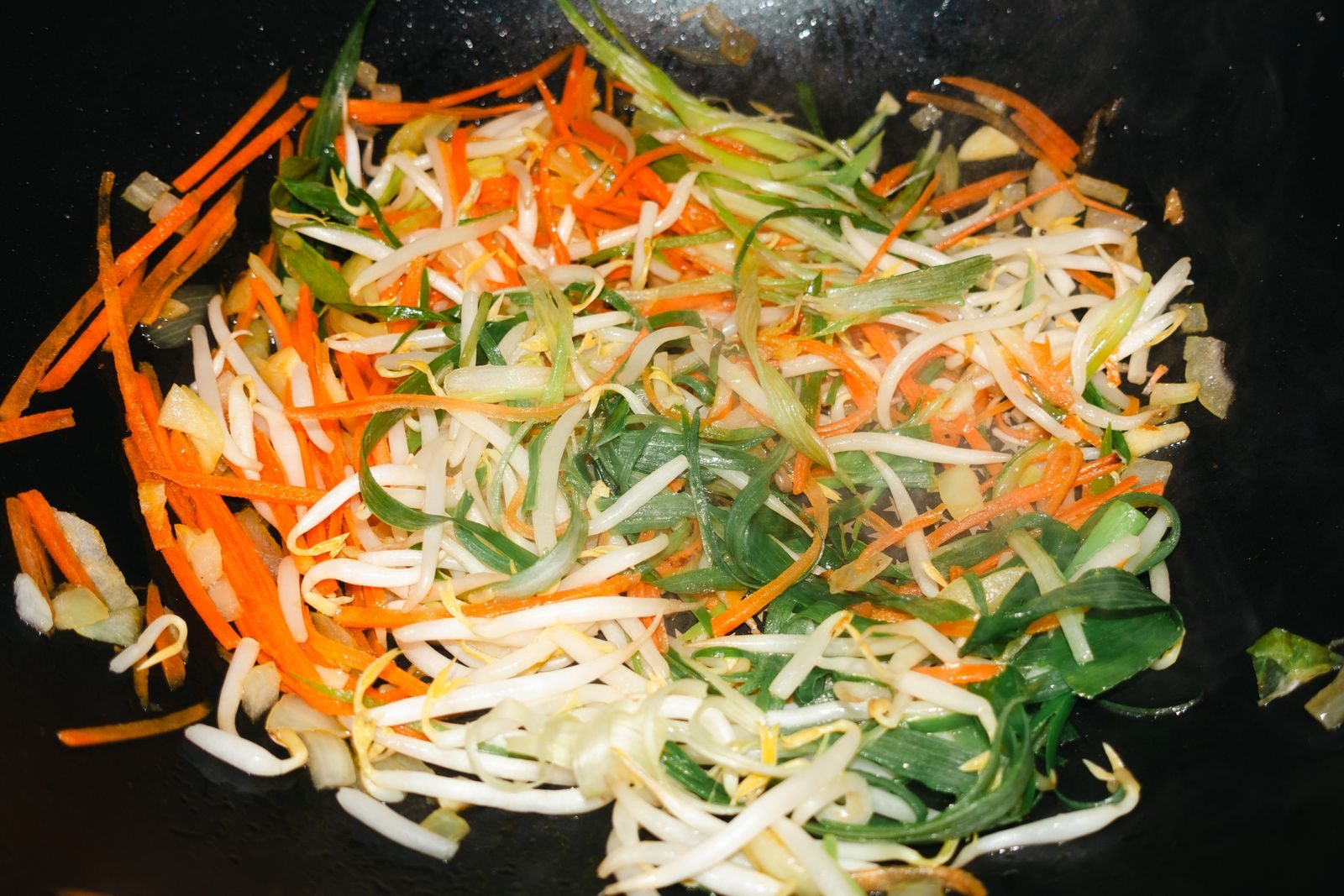 Carrots, bean sprouts and spring onions sizzling in a pan