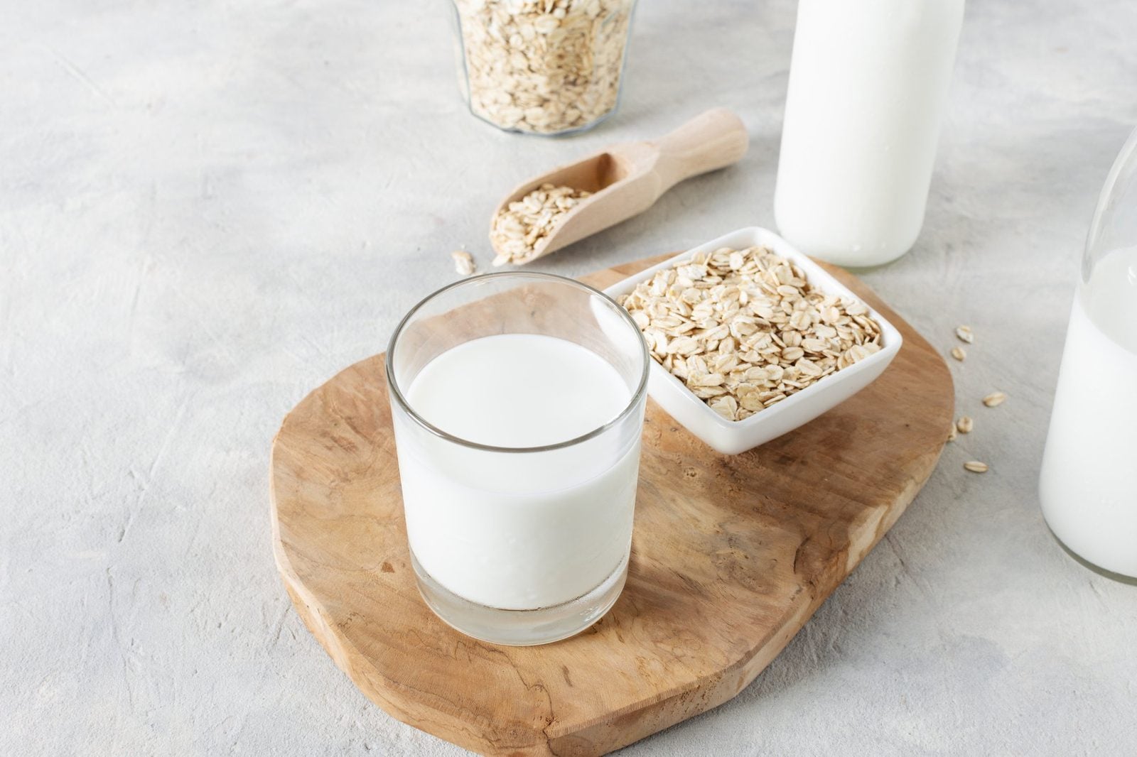 Selbstgemachte Hafermilch im Glas neben einer Schale Haferflocken