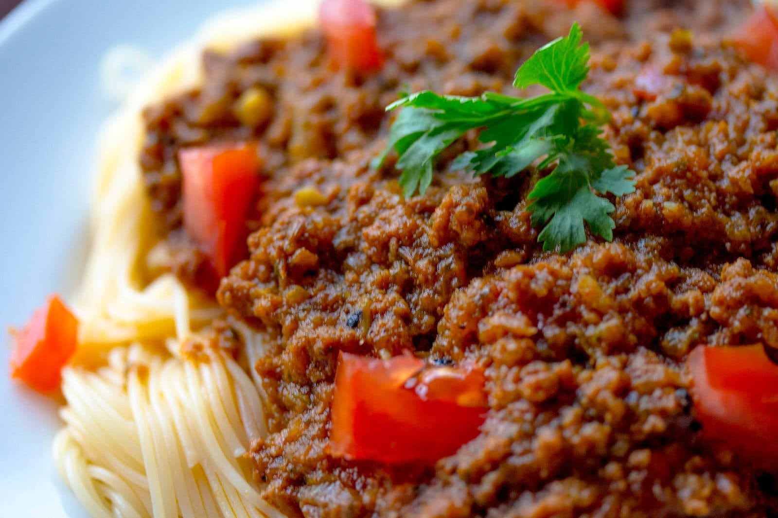 Spaghetti mit Bolognese-Sauce, frischer Petersilie und Tomatenwürfeln in Nahaufnahme