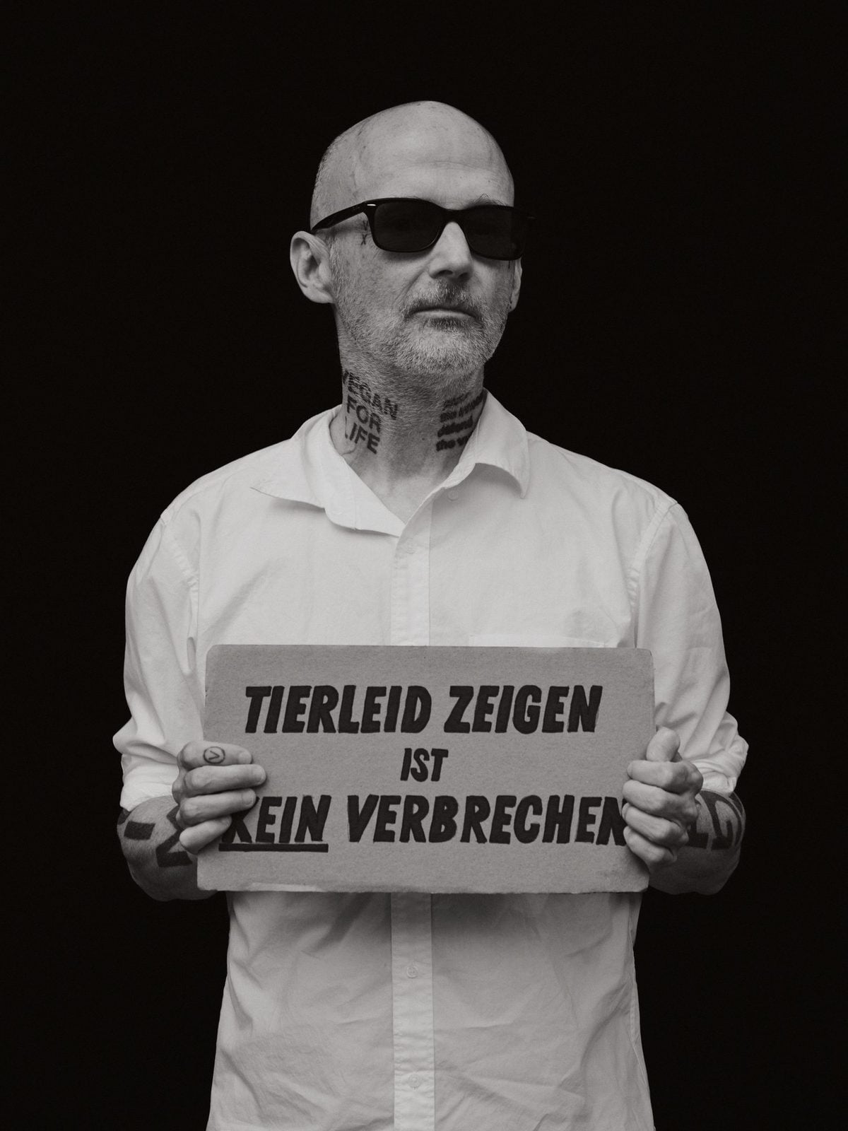 Moby im weißen Hemd hält ein Schild mit der Aufschrift Tierleid zeigen ist kein Verbrechen