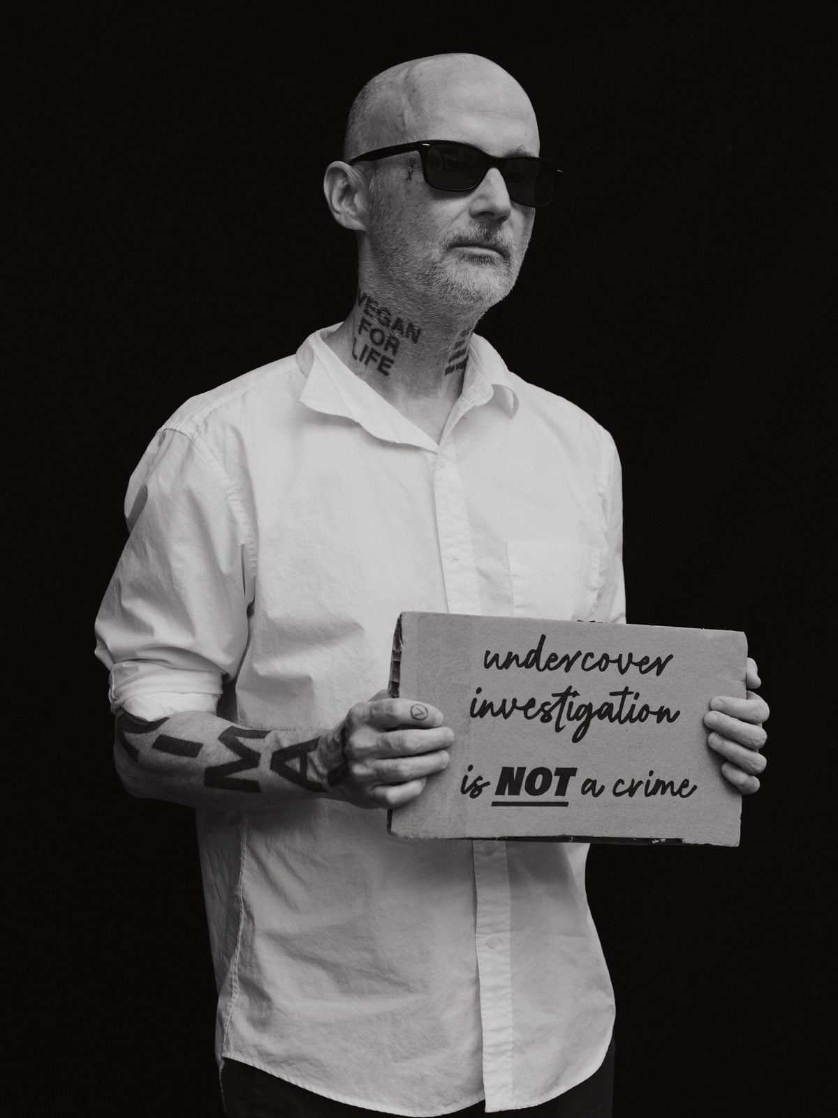 Moby mit Sonnenbrille hält ein Schild mit der Aufschrift undercover investigation is not a crime