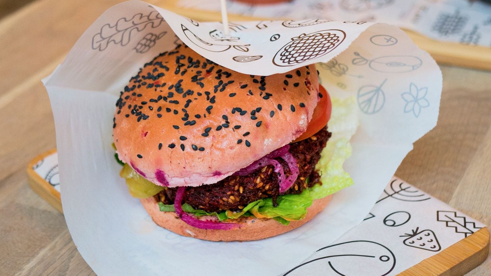 Veggie-Burger mit rosa Brötchen, schwarzem Sesam und körnigem Gemüsepatty