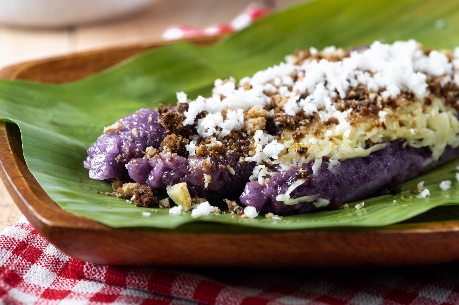 Puto Bumbong, ein violetter philippinischer Reiskuchen auf einem Bananenblatt mit Kokosraspeln