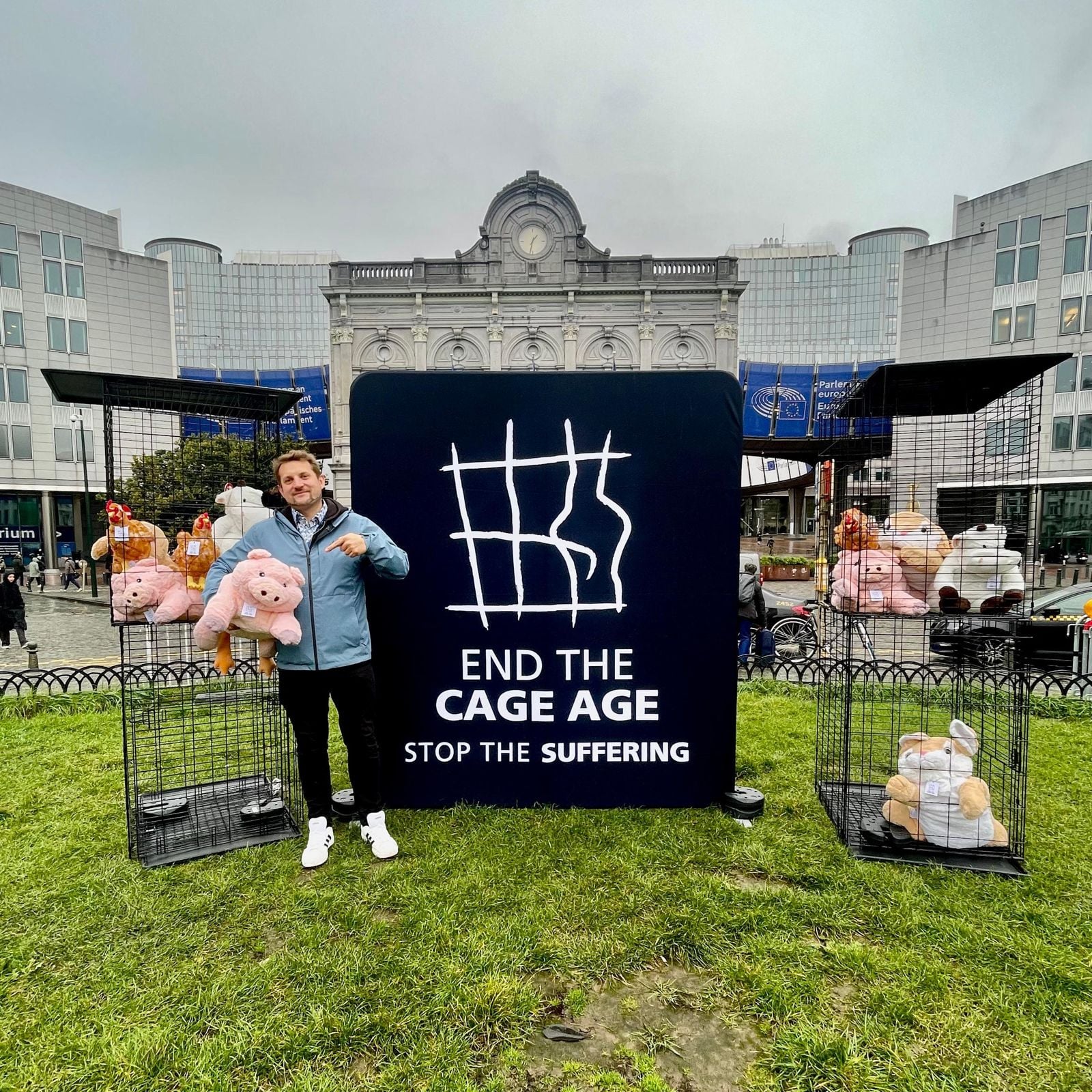 Sebastian Everding vor dem Europäischen Parlament in Brüssel neben einem End-the-Cage-Age-Banner mit Käfigen