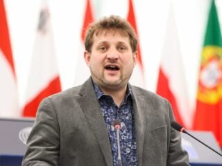 Sebastian Everding spricht am Rednerpult im Plenarsaal des Europaeischen Parlaments, im Hintergrund die Flaggen der Mitgliedstaaten