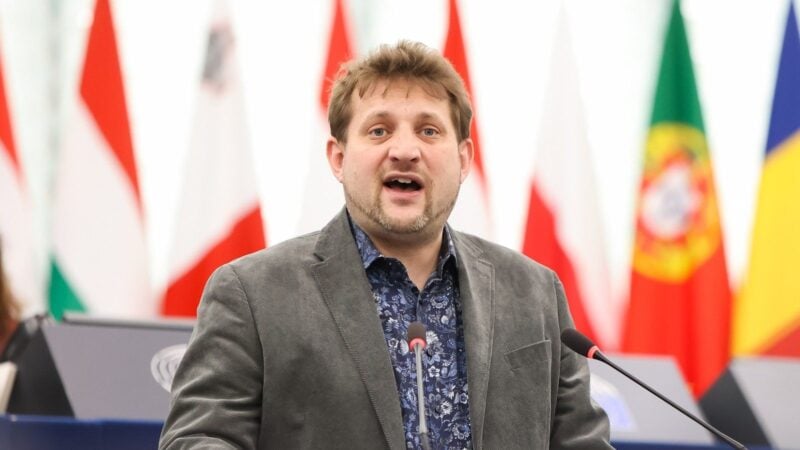 Sebastian Everding spricht am Rednerpult im Plenarsaal des Europaeischen Parlaments, im Hintergrund die Flaggen der Mitgliedstaaten