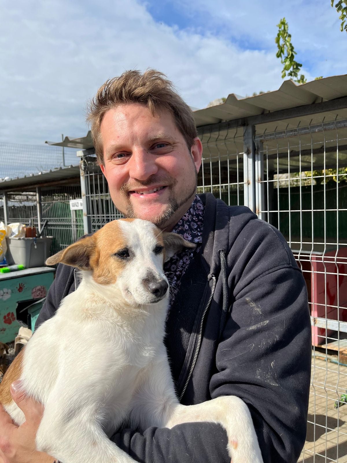 Sebastian Everding hält einen weißen Hund mit braunen Flecken auf dem Arm