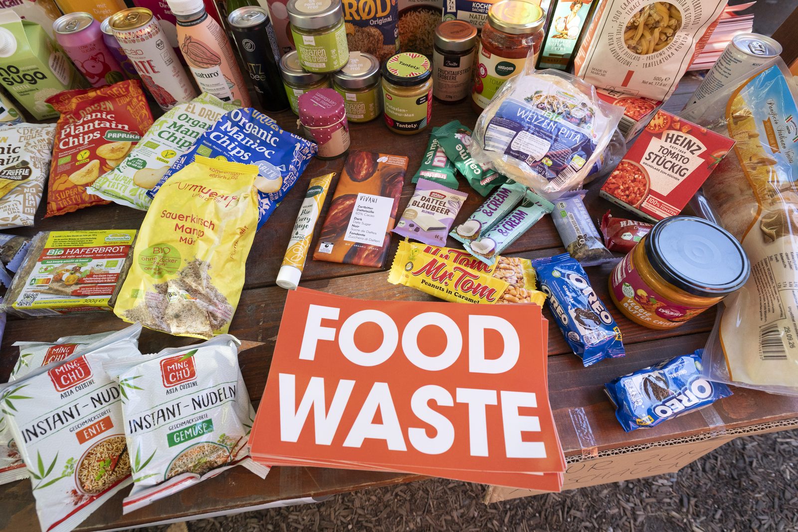 Gerettete Lebensmittel verschiedener Marken rund um ein Schild mit der Aufschrift Food Waste