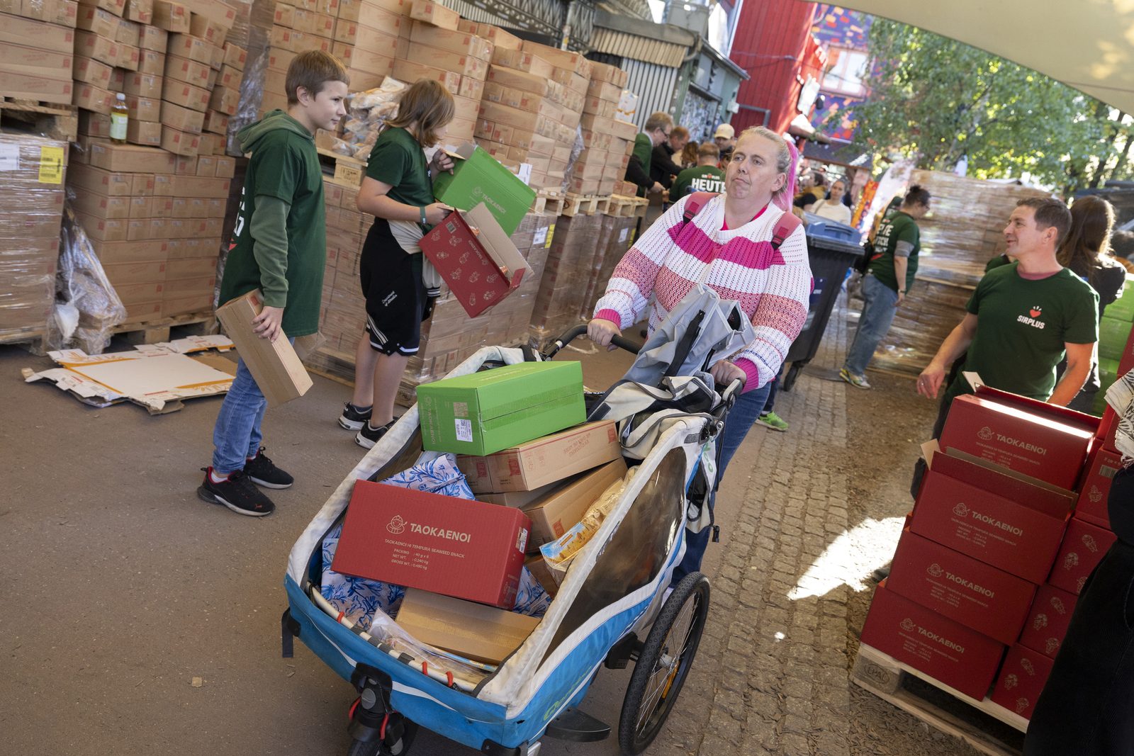 Besucherin belädt ein Lastenrad mit Kartons voller geretteter Lebensmittel