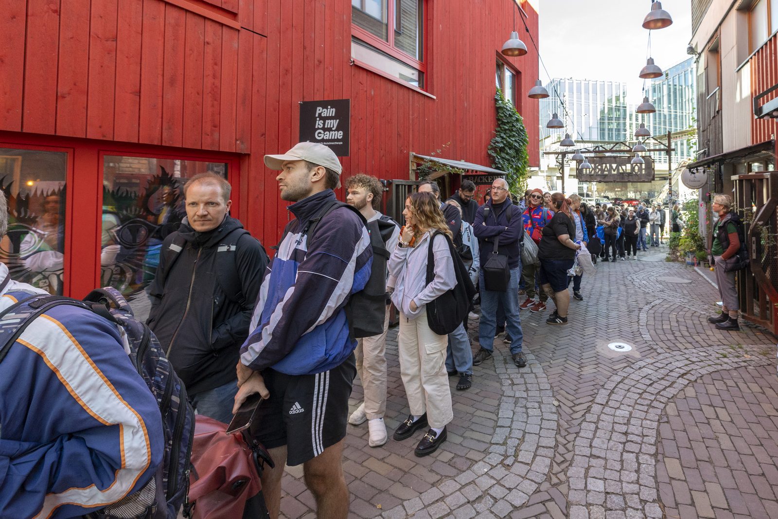 Menschenschlange in einer Gasse zwischen roten Holzhäusern am Holzmarkt
