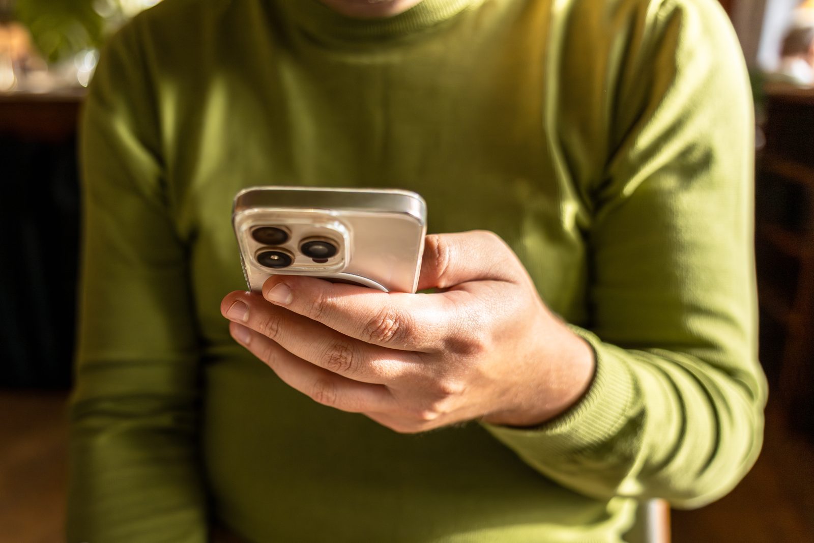 Person scrollt im Café auf dem Smartphone durch Social Media, Symbolbild