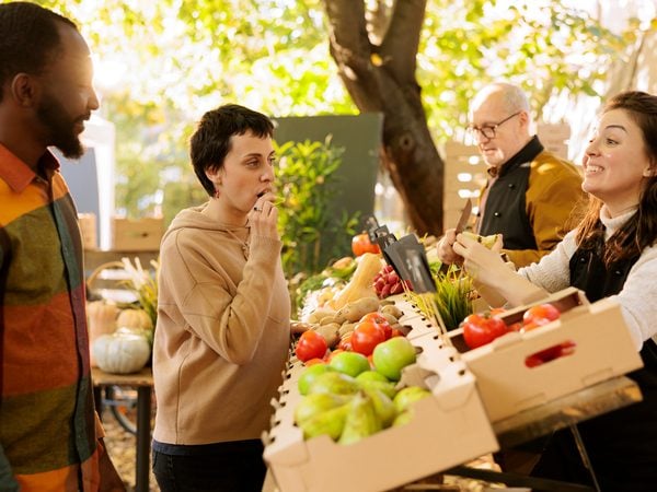 Menschen probieren Obst an einem Marktstand mit frischem Gemüse