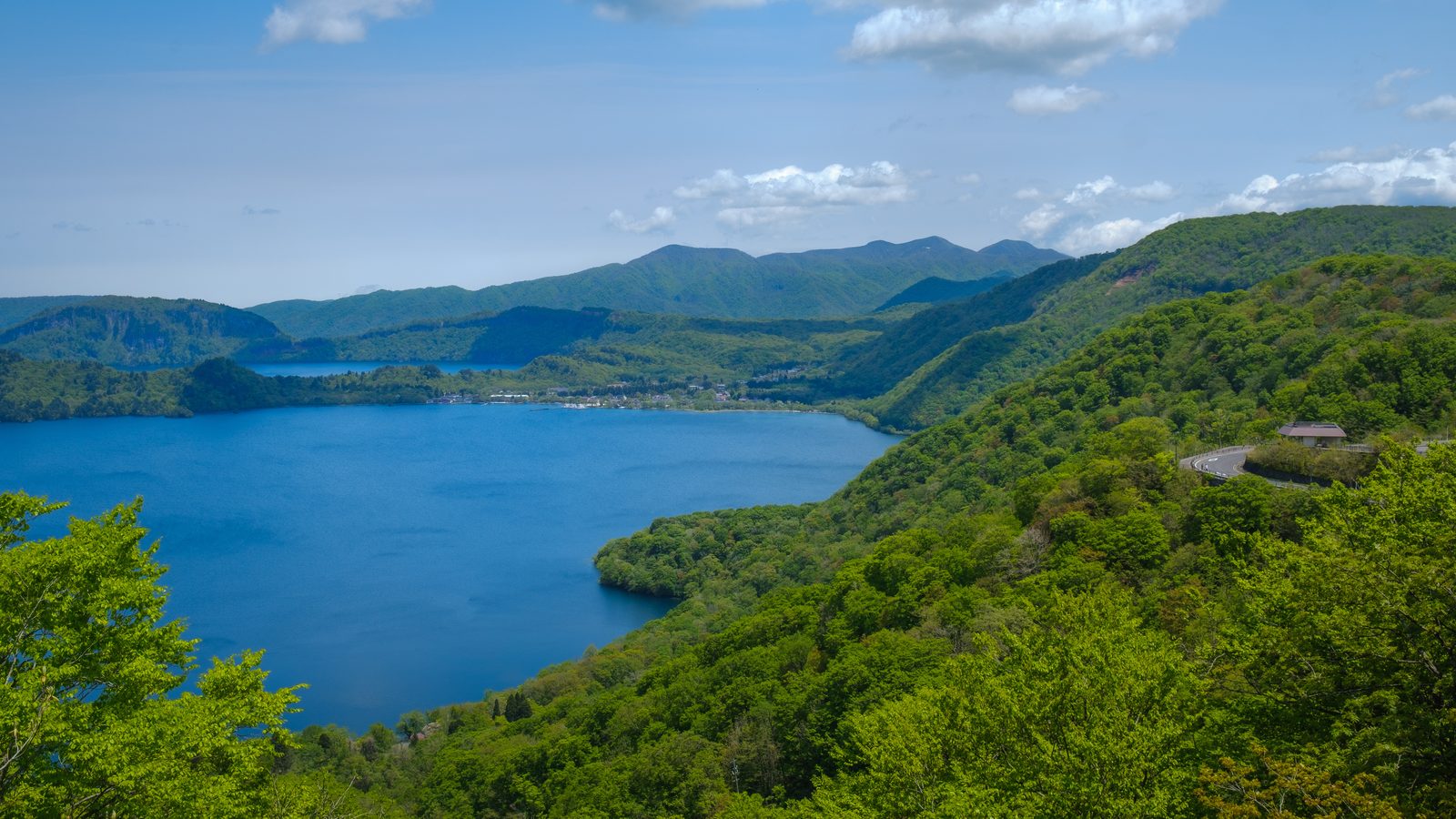 Landschaft in Akita: Blick über den Towada-See mit bewaldeten Ufern und sanften Hügeln im Sommer