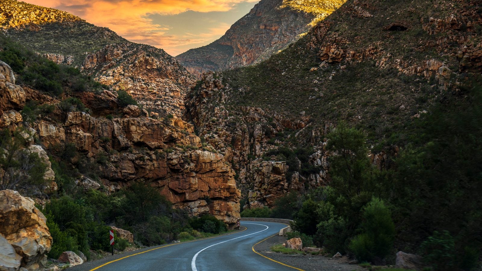 Landschaft in Kleine Karoo: Die Route 62 windet sich durch felsige Berge im Abendlicht