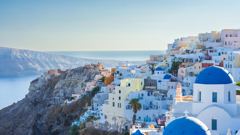 Landschaft in Santorini: Weiße Häuser und blaue Kuppeln von Oia über der Caldera