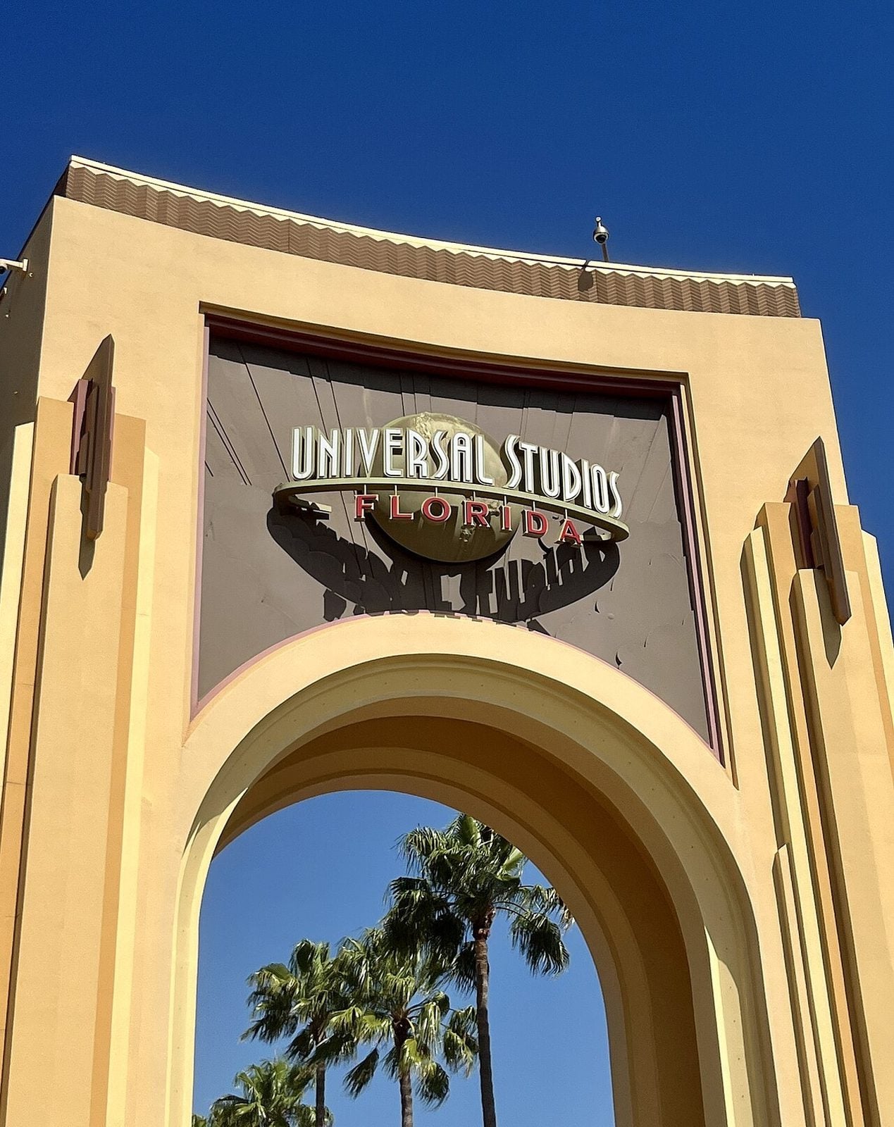 Eingangsbogen des Universal Studios Florida mit dem Schriftzug des Parks vor blauem Himmel