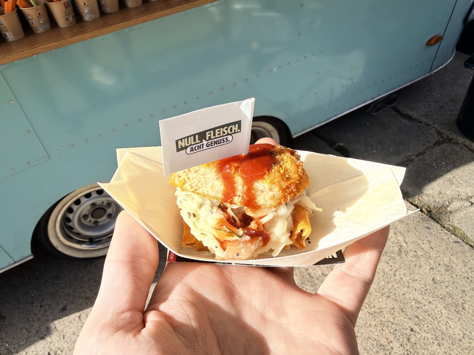 Gefülltes veganes Sandwich in einer Hand vor dem Foodtruck