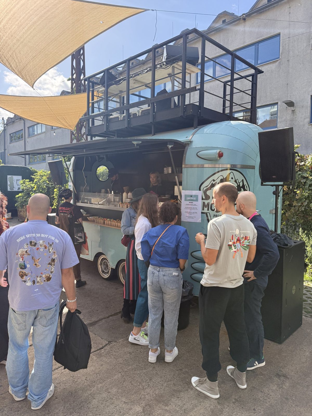 Menschen stehen im Hof vor dem Foodtruck an