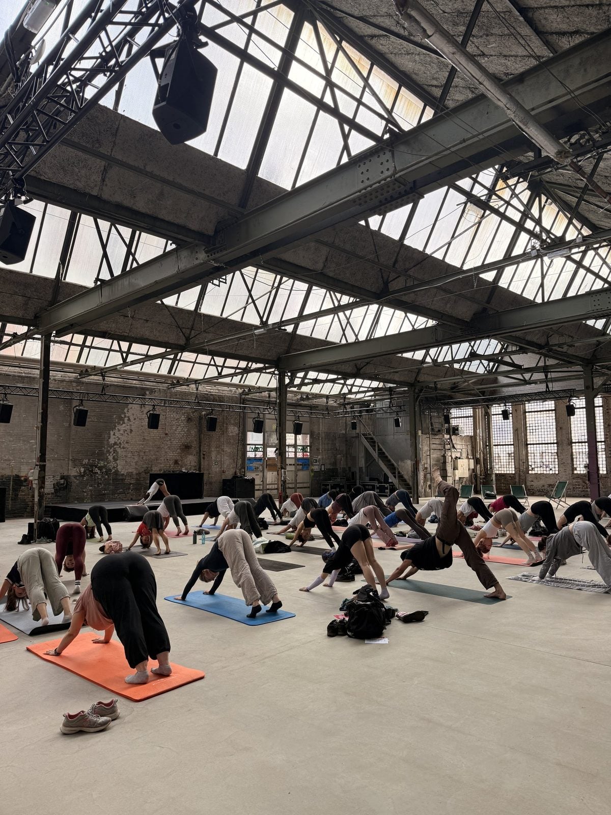 Teilnehmende beim Morgen-Yoga auf Matten in der Halle des Haus der Visionäre