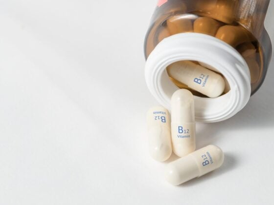 Geöffnete Dose mit Vitamin-B12-Kapseln auf hellem Untergrund