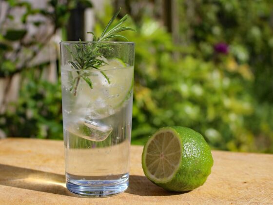 Alkoholfreies Tonic mit Rosmarin und Limette im Glas auf einem Holztisch