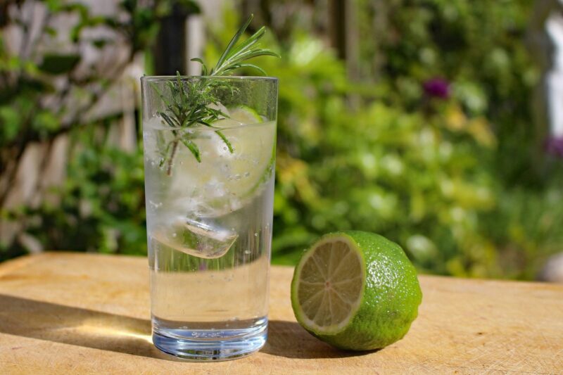 Alkoholfreies Tonic mit Rosmarin und Limette im Glas auf einem Holztisch