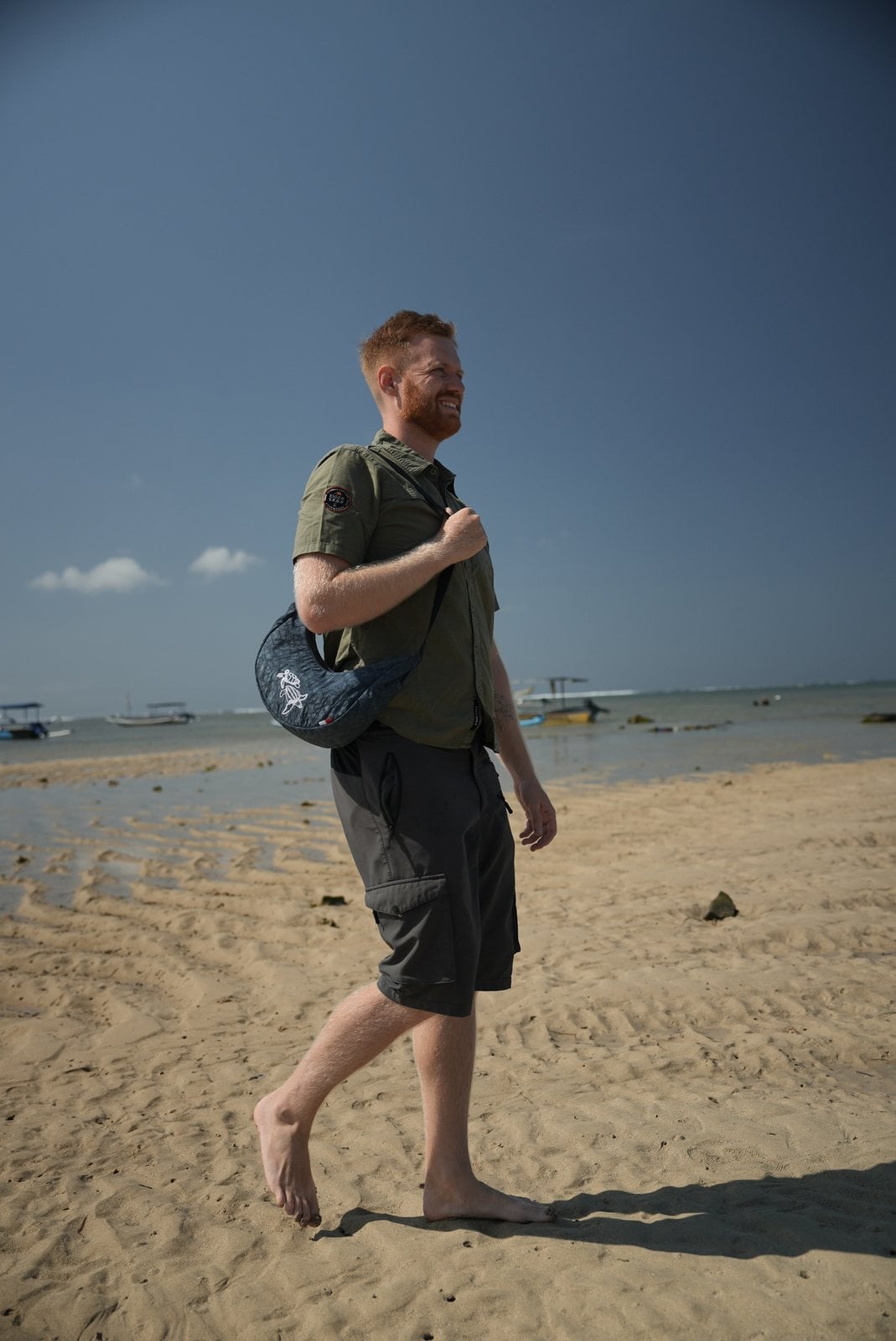 Mann geht mit dem Turtle Moonbaq Mini über den Strand