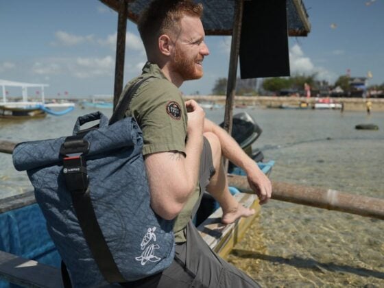 Manuel Bergmann sitzt mit dem Turtle Rolltop von Airpaq auf einem Boot und blickt aufs Meer