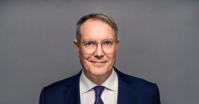 Porträt von Alexander Schweitzer (SPD) im dunkelblauen Anzug vor grauem Hintergrund