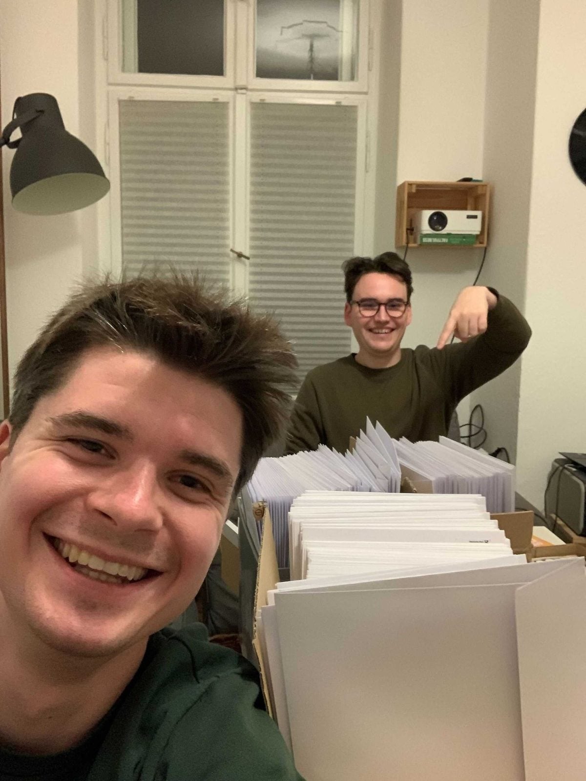 David Gaedt und ein Teamkollege zwischen Kartons mit Printausgaben des Good News Magazins