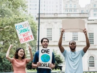 Drei junge Menschen demonstrieren mit Schildern für den Klimaschutz