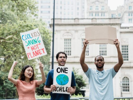 Drei junge Menschen demonstrieren mit Schildern für den Klimaschutz