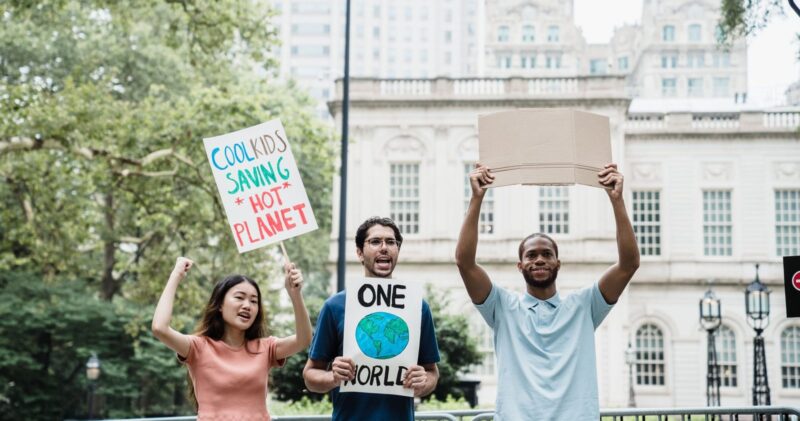 Drei junge Menschen demonstrieren mit Schildern für den Klimaschutz