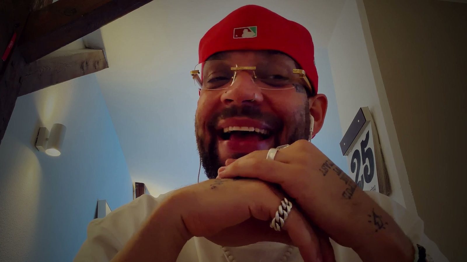 FAYAN lacht herzhaft, die Hand mit Ringen und Tattoos am Kinn