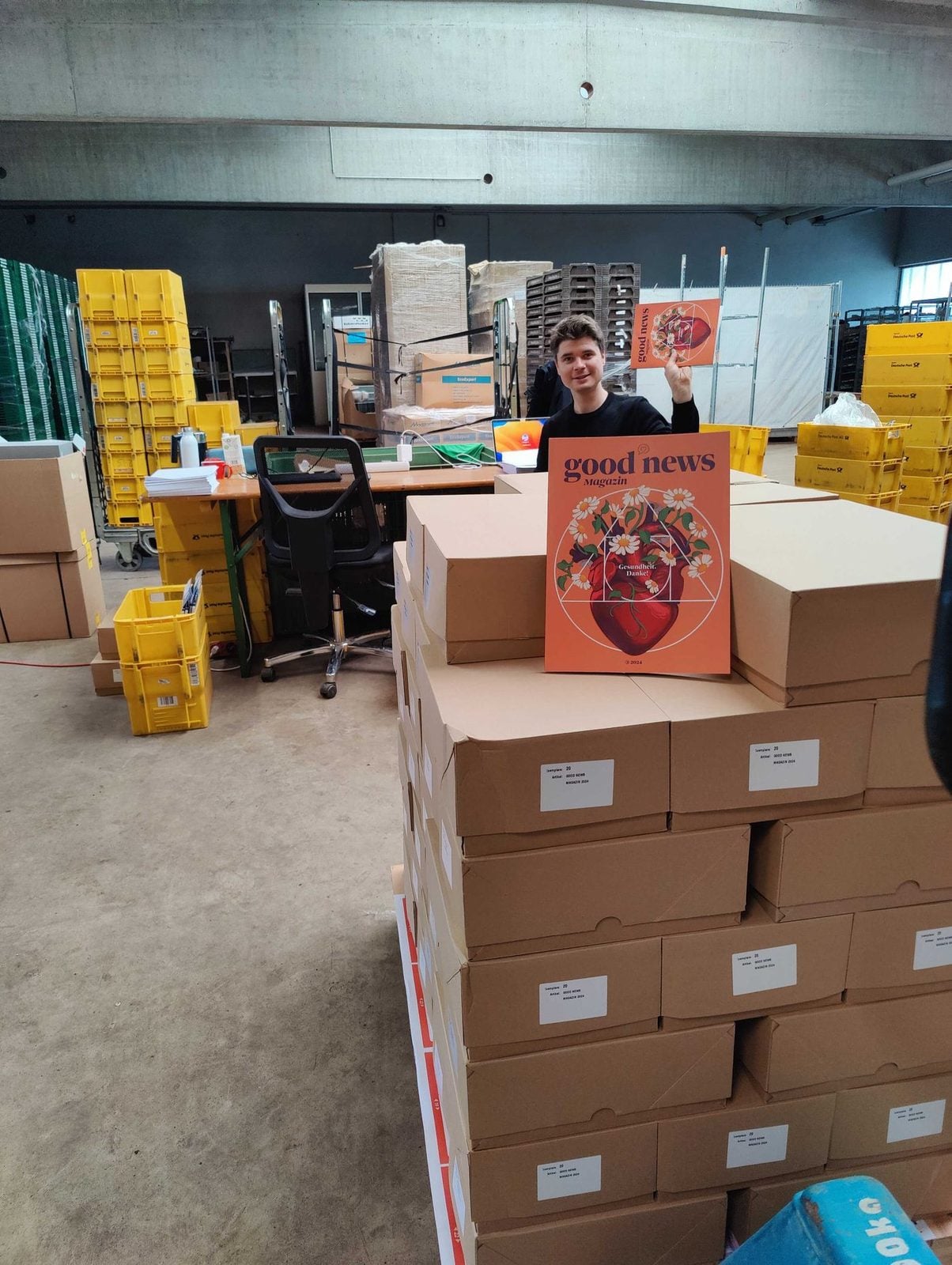Kartons mit Printausgaben des Good News Magazins in einem Lager