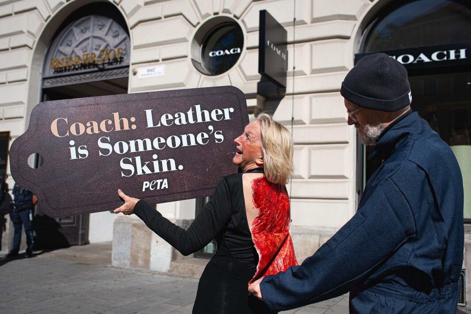 Ingrid Newkirk mit einer aufgemalten Wunde am Rücken und einem Schild vor der COACH-Filiale in München