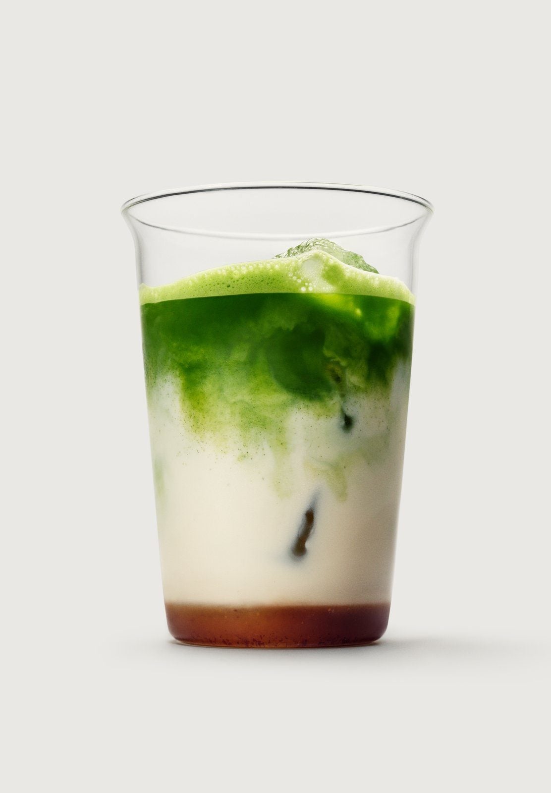 Ein Glas mit Eis, Haferdrink und grünem Matcha, unten eine Schicht Dattelsirup